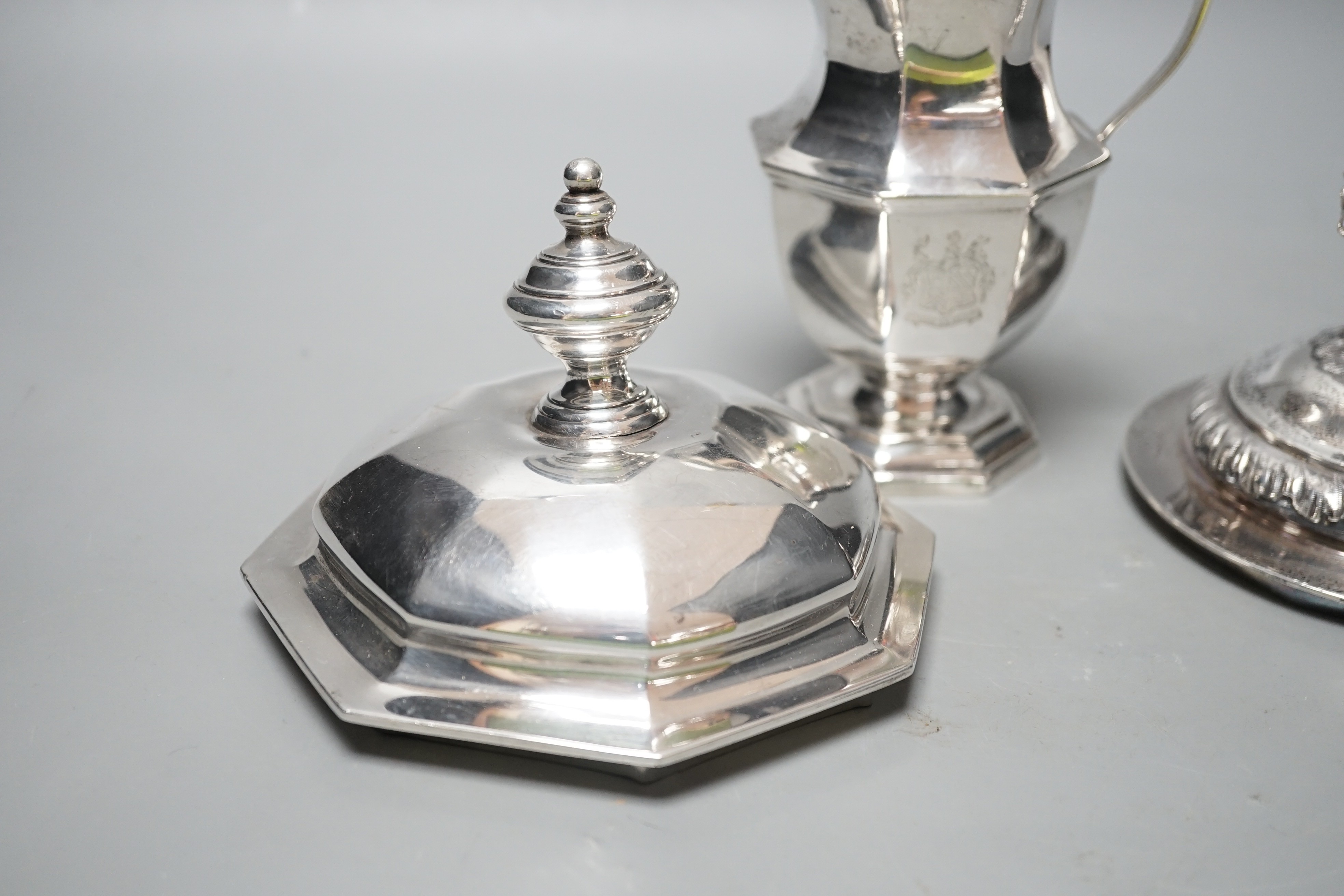 A 20th century silver cream jug by Mappin & Webb(date letter rubbed), height 13.9cm and two Victorian trophy cup covers, one with sheep finial, 24.8oz.